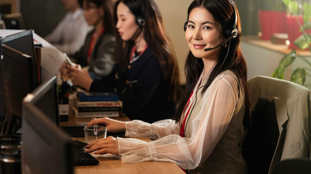 Smiling support agents wearing headsets at computers, ready to take over from the chatbot