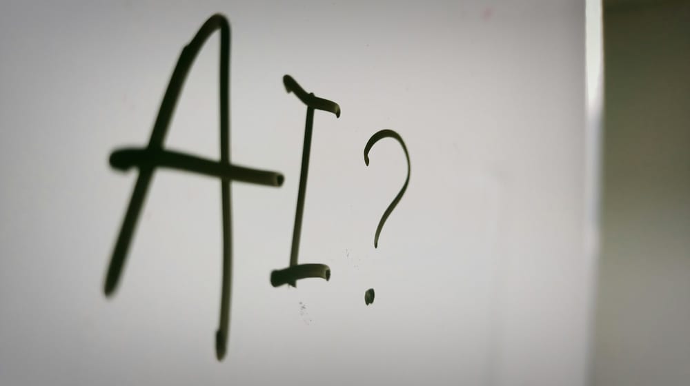 The question AI? written in marker on a whiteboard, as content teams weigh up AI