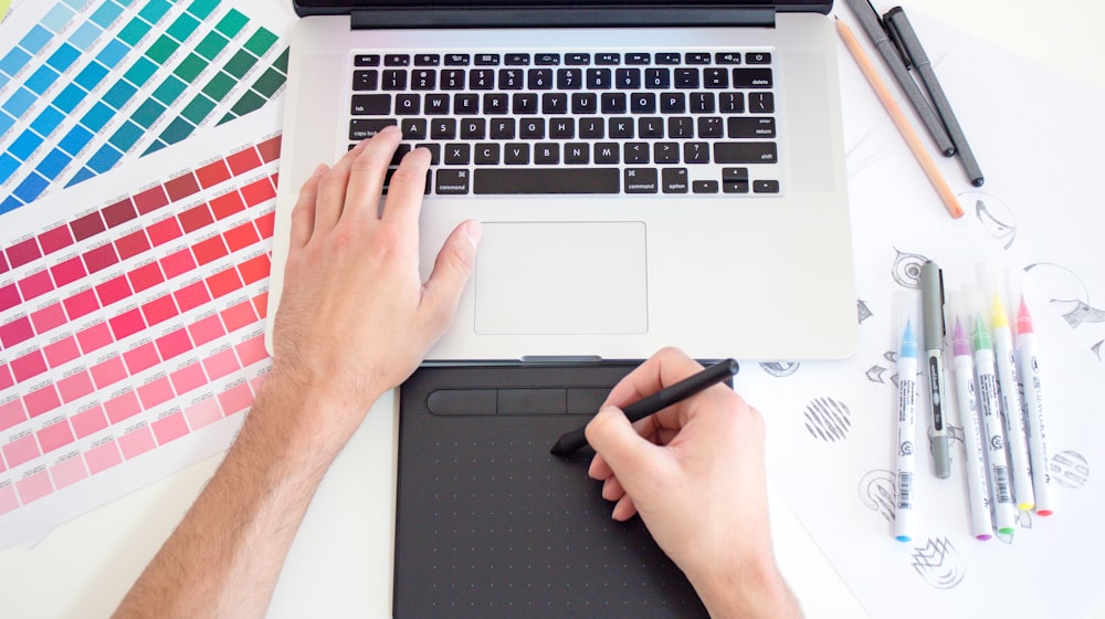 Designer working across a tablet and laptop on interface layouts
