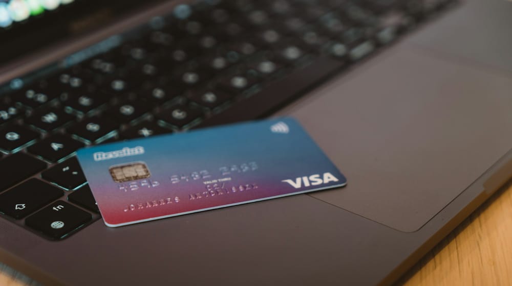 Debit card resting on a laptop keyboard, moments before a shopper completes checkout