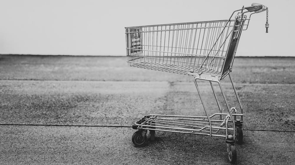 Empty shopping trolley on grey ground, the cost of shoppers abandoning a slow store
