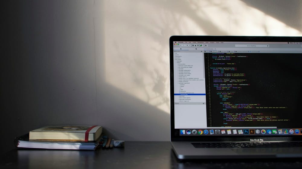 MacBook on a desk showing programming code for a type-safe full-stack web project
