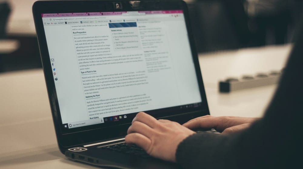 Hands typing on a laptop while editing a document, like building pages in the Site Editor